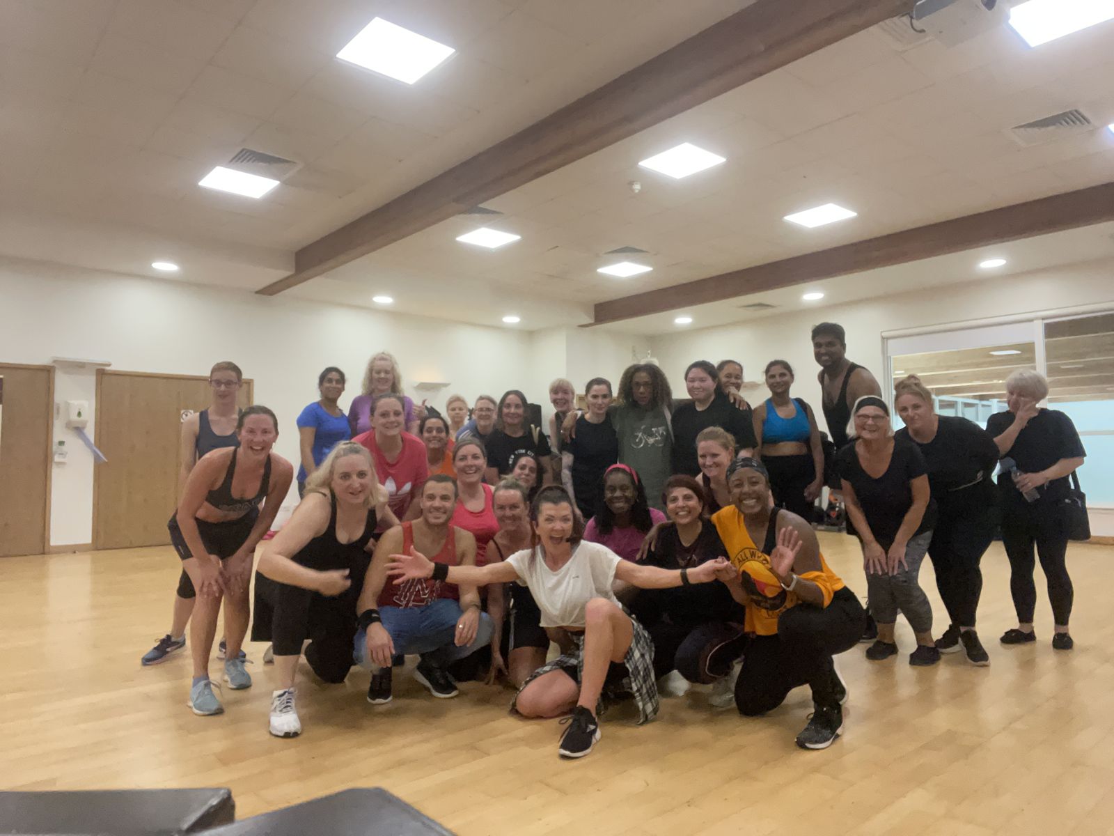 A packed studio of class members celebrating after a dance fitness class